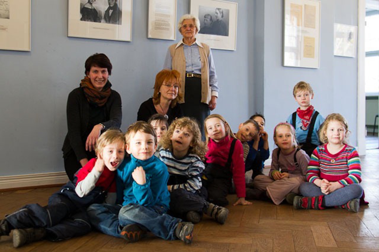 Kuratorin Steffi Katschke (links) und die ehemalige Bloch-Schülerin Emmi Kaminski (hinten) mit Kindern der Tagesstätte Marie Bloch