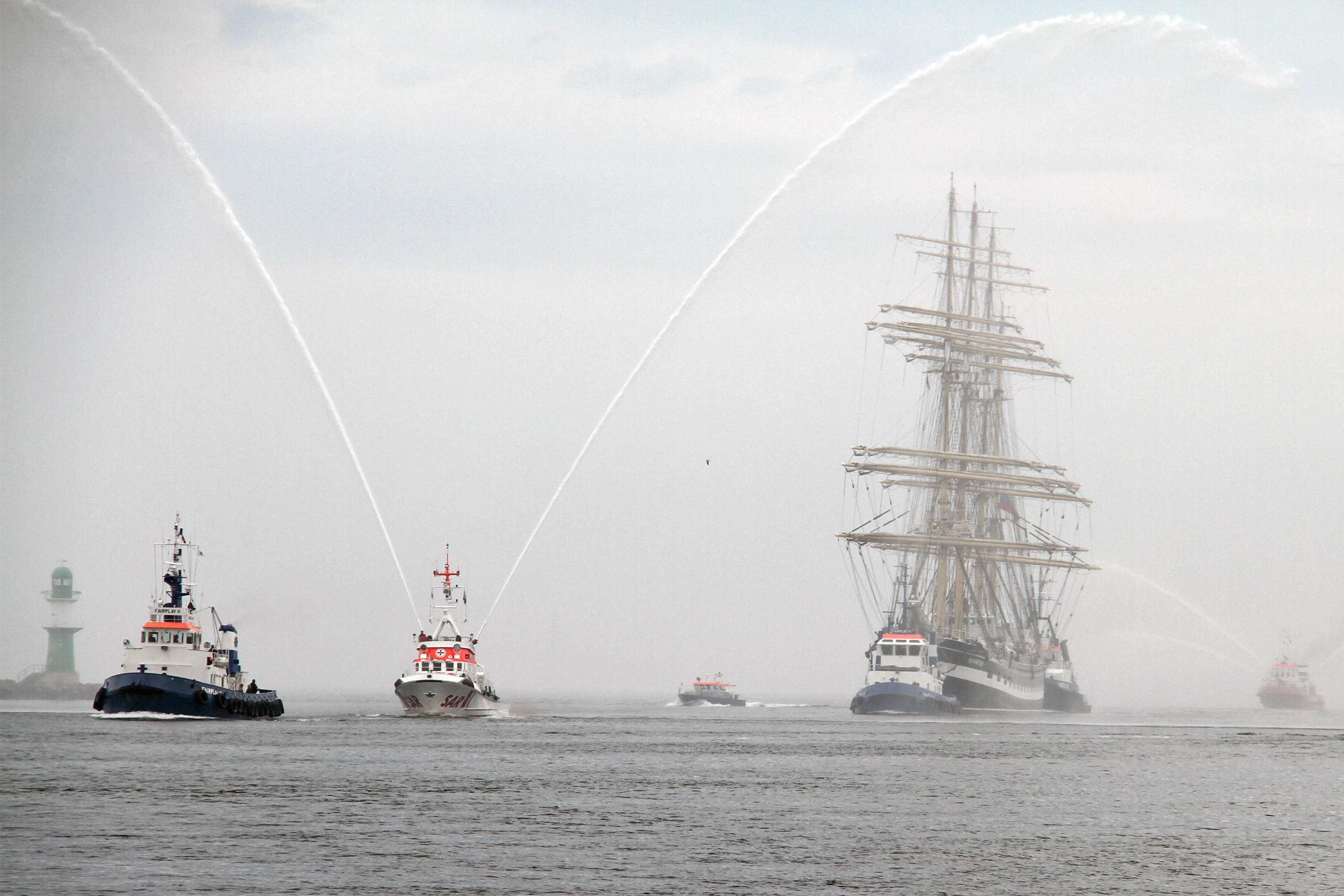 „Krusenstern“ beim Einlaufen in Warnemünde - vorweg der Seenotkreuzer „Arkona“, im Hintergrund das Feuerlöschboot „Flb 40-3“