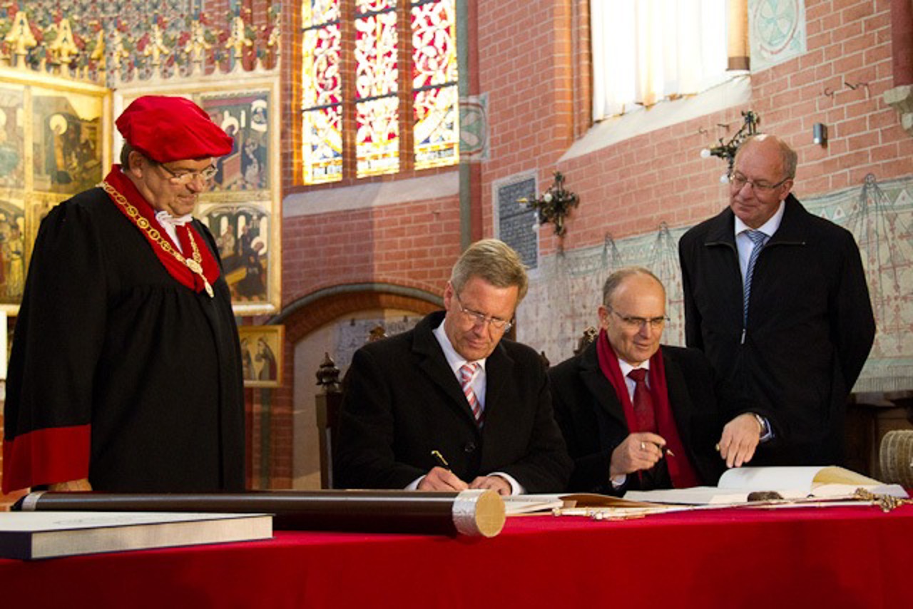 Bundespräsident Christian Wulff und Ministerpräsident Erwin Sellering tragen sich in der Universitätskirche Rostock in die Gästebücher ein