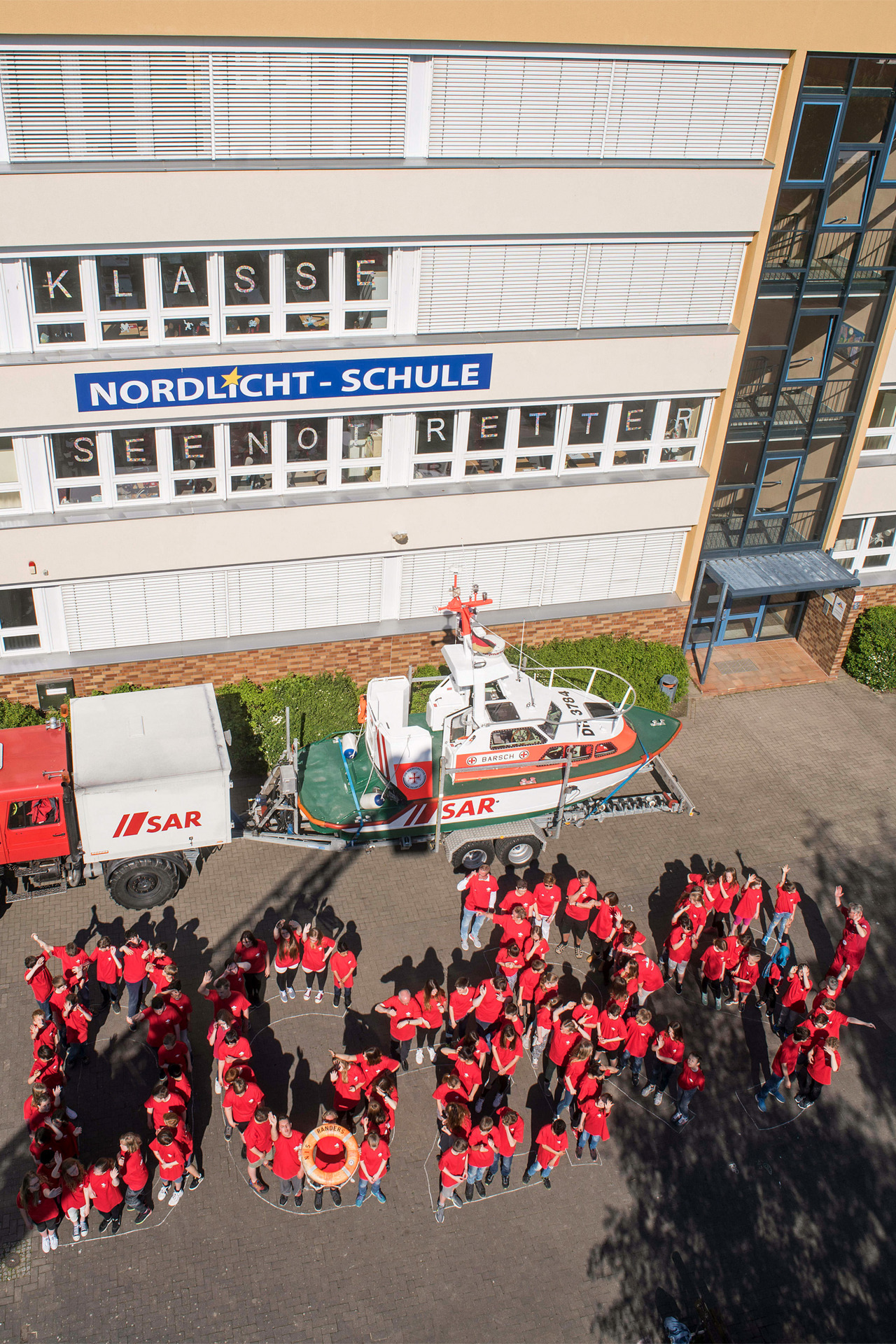 Vor dem Boddenbootgespann der Freiwilligen-Station Wustrow bilden Mädchen und Jungen der Nordlicht-Schule die Buchstaben DGzRS, die Abkürzung für die Deutsche Gesellschaft zur Rettung Schiffbrüchiger (Foto: DGzRS/Frank Hormann)