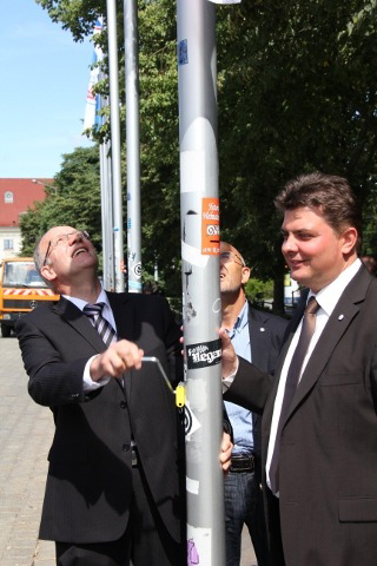 Roland Methling und Bernd Hofmann hissen die Hansa-Flagge vor dem Rathaus