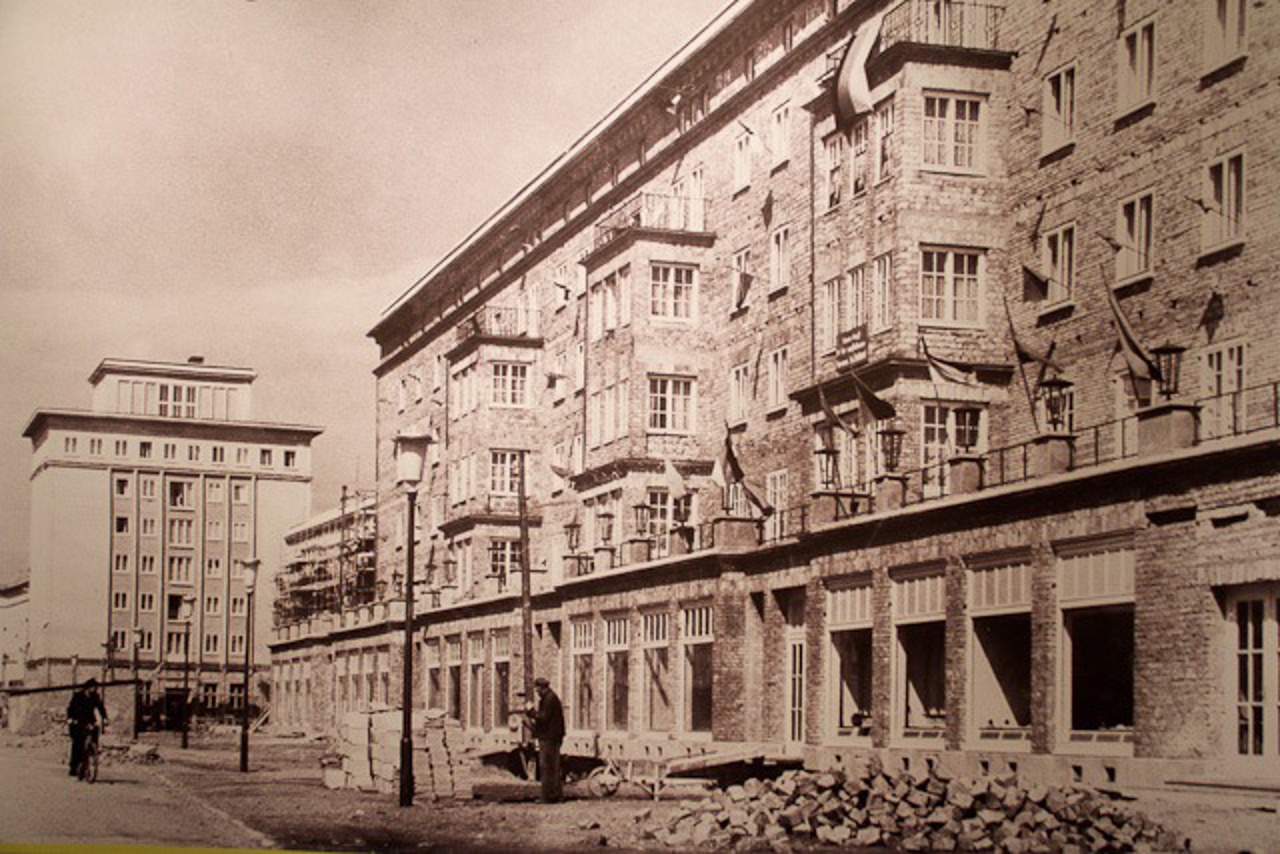 Die Ernst-Thälmann-Straße in Reutershagen: in der Aufnahme von HIldegard Levermann-Westerholz aus dem Jahr 1957/58 sieht man die unverputzte Fassade der Stein auf Stein gemauerten Häuser mit Fahnen zum 1. Mai. (Repro.)