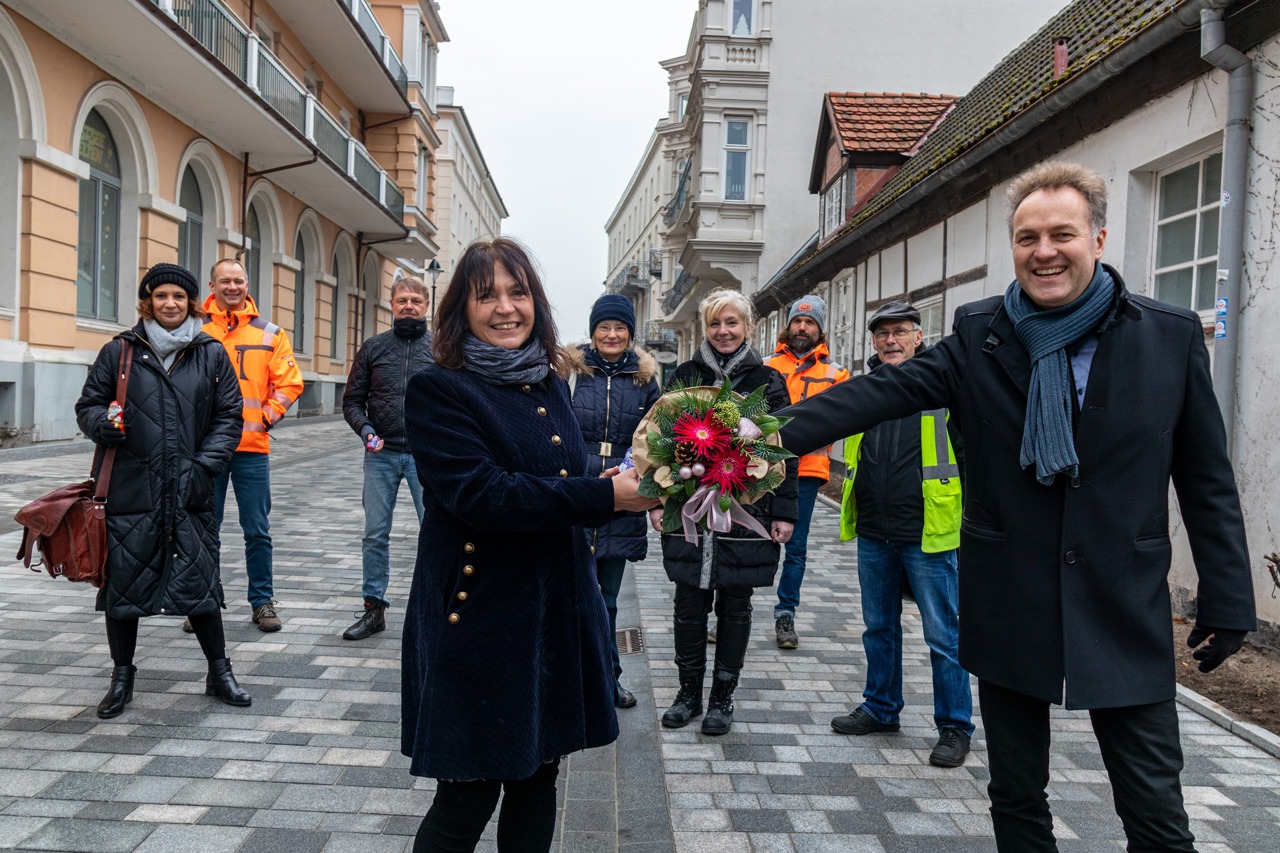 Bausenator Holger Matthäus übergibt Anliegerin Ines Heinrich einen Blumenstrauß zur Sanierung der Georginenstraße in Warnemünde