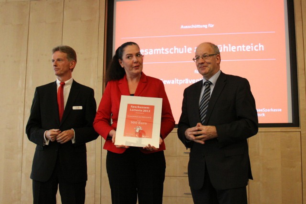 Frank Berg von der OSPA und Oberbürgermeister Roland Methling übergeben Schulleiterin Susanne Heinz die Spendentafel