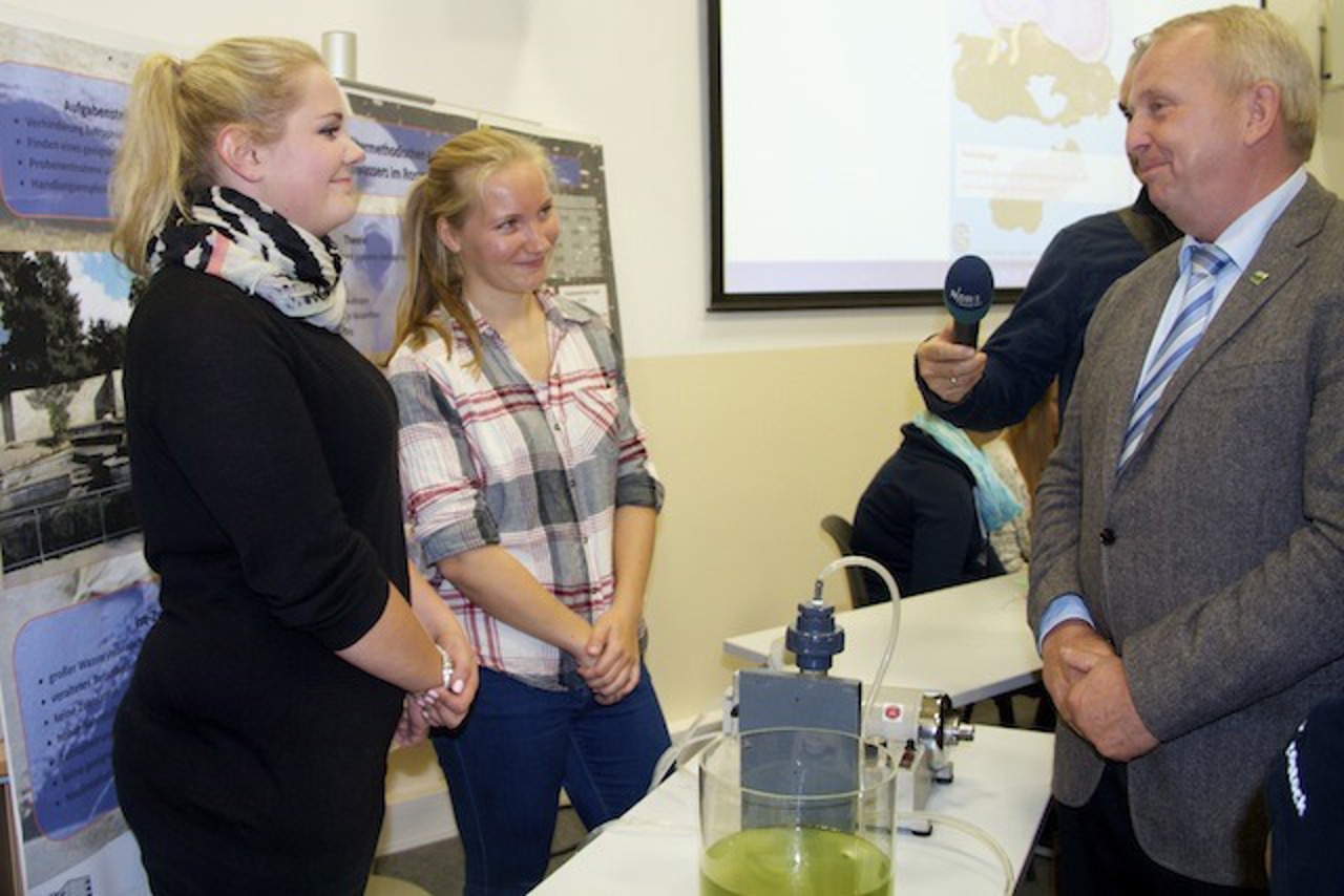 Anna Diederich und Friederike Eggert erläutern Landschaftsminister Till Backhaus die von ihnen entwickelte Filtermethode zur Wasseraufbereitung