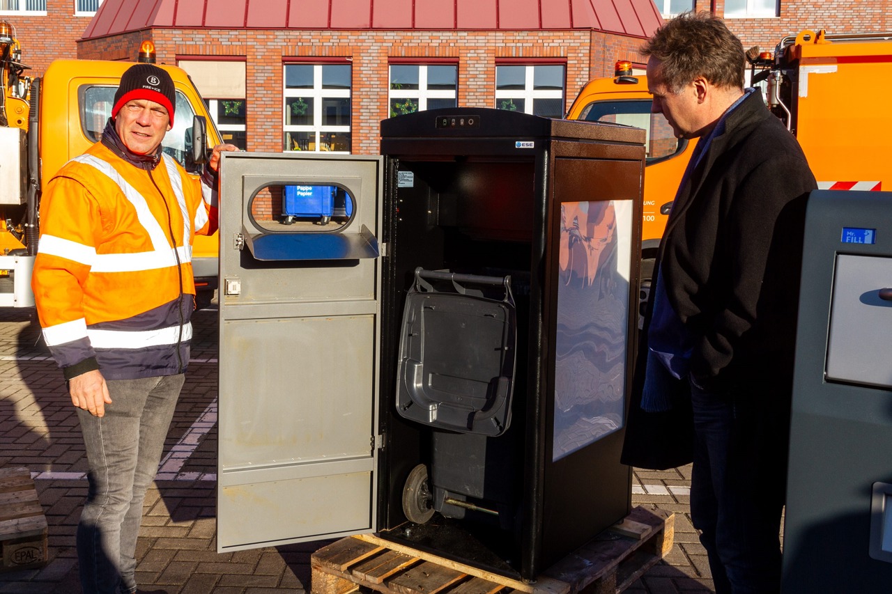 René Weilandt zeigt Umweltsenator Holger Mattäus das Innenleben. Unten befindet sich eine normale 120-Liter-Tonne. (Foto: Archiv)