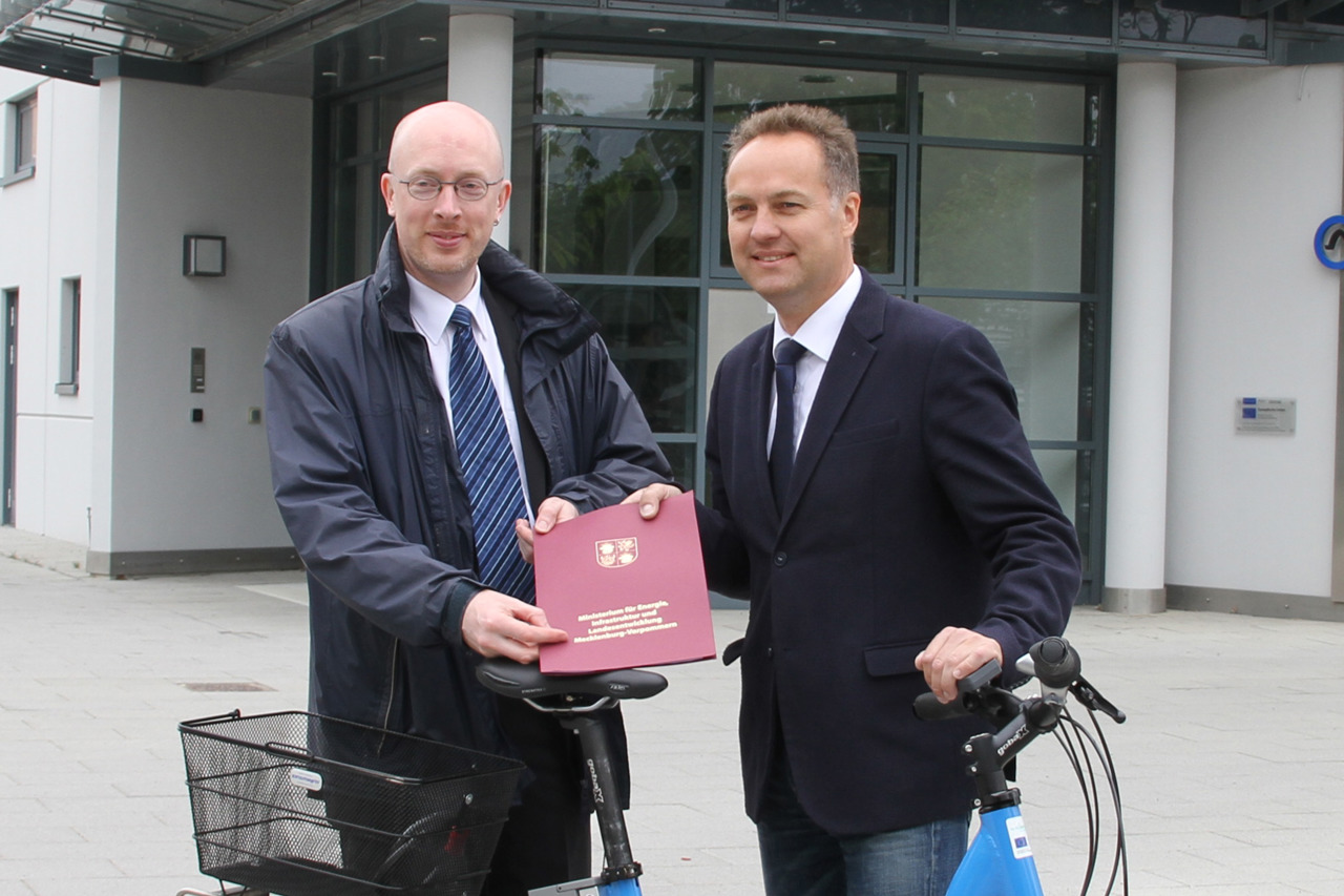 Infrastrukturminister Christian Pegel (links) übergibt Bau- und Umweltsenator Holger Matthäus einen Förderbescheid für die Potenzialanalyse zu den Rostocker Radschnellwegen