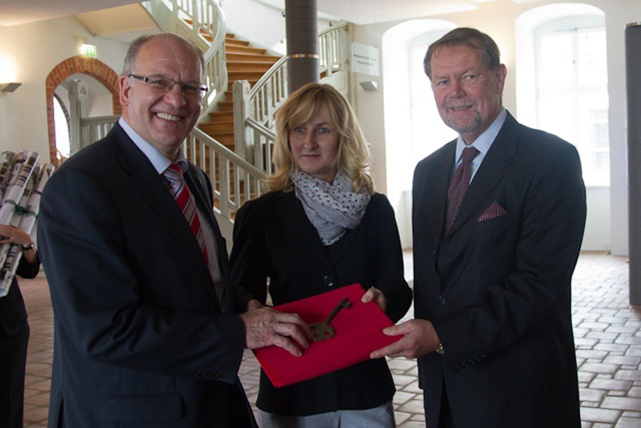 Oberbürgermeister Roland Methling und Sigrid Hecht von der KOE nehmen den symbolischen Schlüssel von Reinhard Wolfgramm von der RGS entgegen