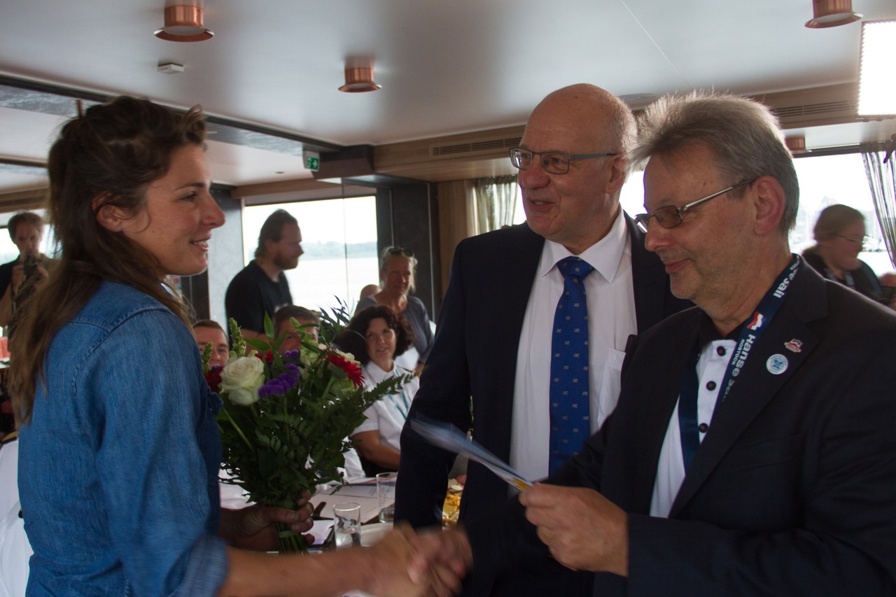 Frank Elsner und Roland Methling begrüßen die Kapitänin der Nordlys Anne Flore Gannat (v.r.n.l.)