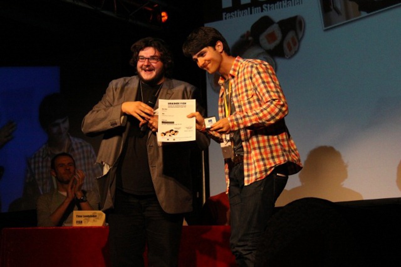 Moderator und Filmemacher Axel Ranisch übergibt Stephan Kämpf die Silbermedaille für "Chaos"