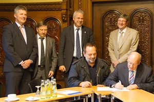 Rostocks Oberbürgermeister Roland Methling und Thomas Leuchert, Landrat des Landkreises Rostock, unterschreiben den Kooperationsvertrag umgeben von weiteren Vertretern der Regiopol-Partner