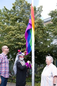 Rosa la Ola Grande hisst die Regenbogenflagge vor dem Rathaus, links Mathias Luther