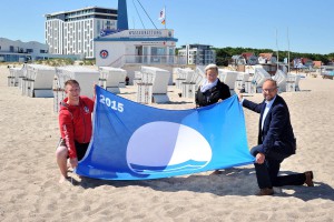 Tony Wilken (DRK Wasserwacht), Ursula Klause und Tourismusdirektor Matthias Fromm (beide Tourismuszentrale Rostock & Warnemünde) (v.l.n.r.) freuen sich über die erneute Auszeichnung mit der „Blauen Flagge“ (Foto: Joachim Kloock)