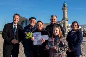 Monika Tuchen mit Tochter Vivien (vorne) ist die 80.000. Besucherin 2019 auf dem Warnemünder Leuchtturm - es gratulieren Holger Matthäus (Senator für Bau und Umwelt), Leuchtturmvereinschef Klaus Möller, Stellvertreter Mathias Stagat und Schatzmeisterin Ingelore Morenz