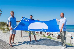 Die Blaue Flagge weht wieder in Markgrafenheide und Warnemünde - Henry Klützke (Ortsbeiratsvorsitzender Markgrafenheide), Manuel Brumme (Wachtdienstkoordinator DRK Wasserwacht) und Tourismusdirektor Matthias Fromm (Foto: Julia Junge/DRK)